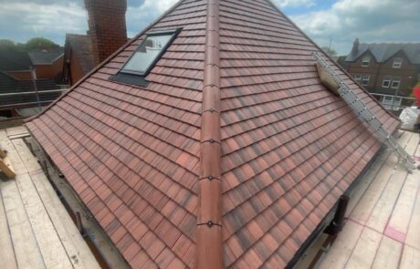 Skilled roofers hand-cutting & double-fixing premium natural slate tiles on a traditional stone cottage in rural Northumberland.