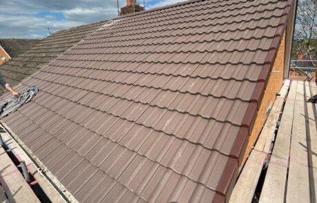 Close-up of experienced roofers installing high-density concrete interlocking tiles & dry verge systems on a semi-detached home in Sunderland.
